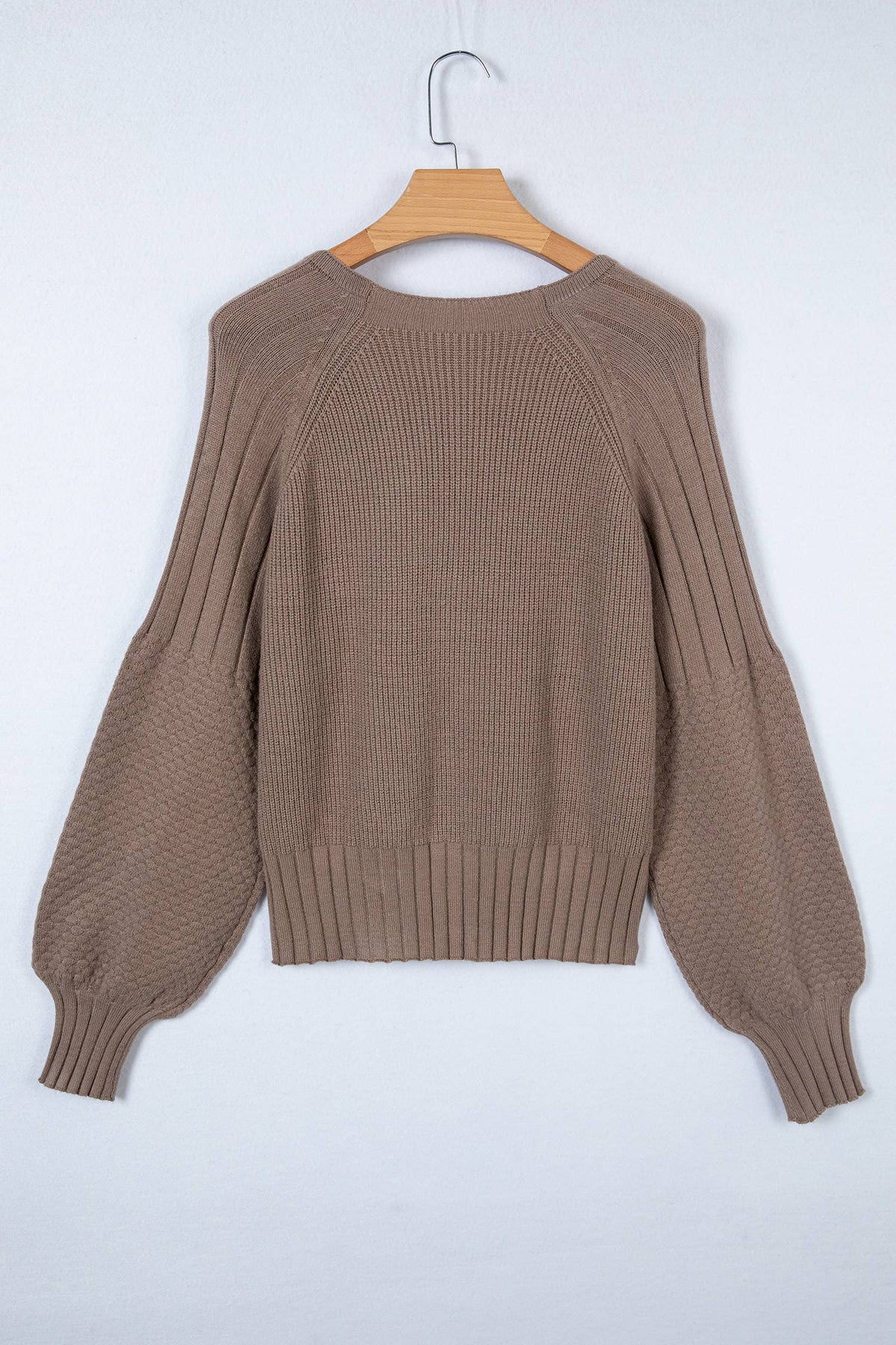 Brown sweater on a wooden hanger against a white background