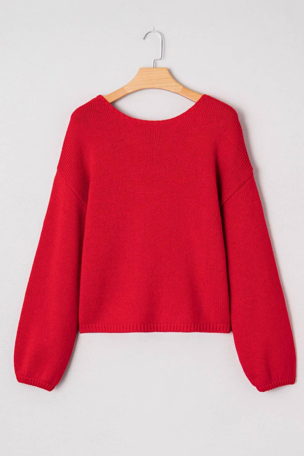 Red sweater on a wooden hanger against a white background