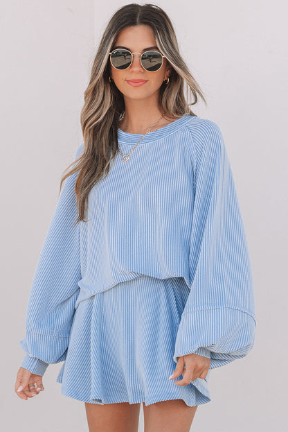 Woman wearing a light blue striped outfit with sunglasses on a plain background