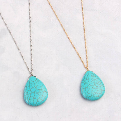 Two turquoise teardrop pendants on gold and silver chains against a white background