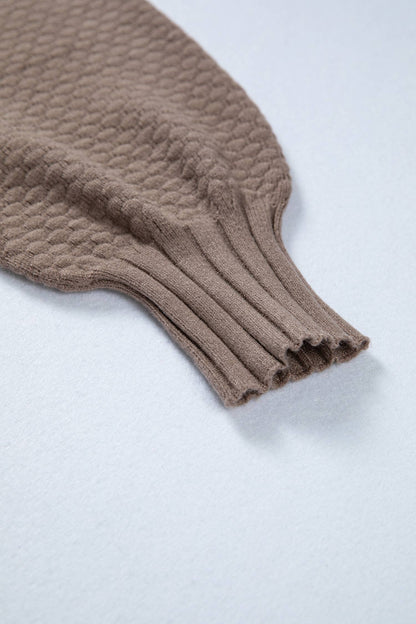 Close-up of a brown knitted sweater sleeve on a light gray background