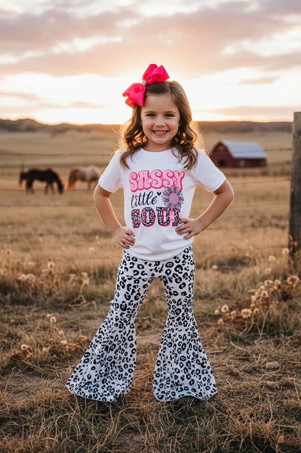 Young girl in a field wearing a 'Sassy Little Soul' shirt and leopard print pants.