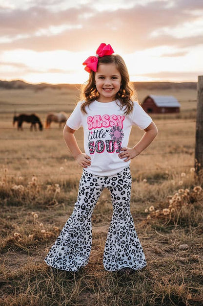 Young girl in a field wearing a 'Sassy Little Soul' shirt and leopard print pants.