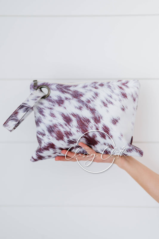 Maroon and white tie-dye pouch held by a hand on a light gray background