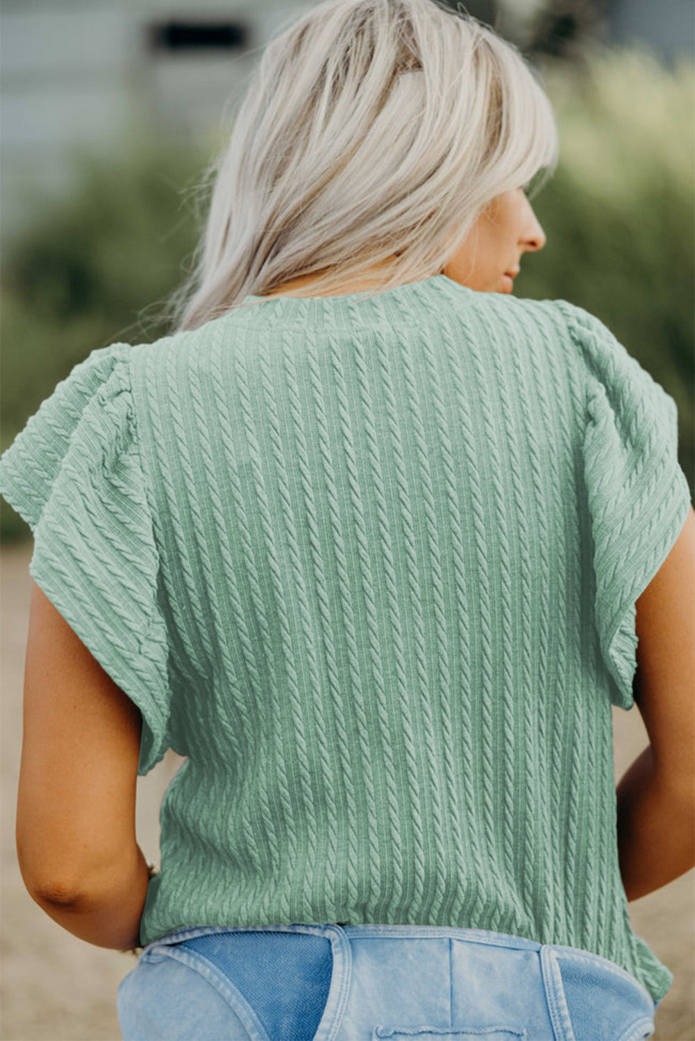 Woman wearing a green textured top with blurred background