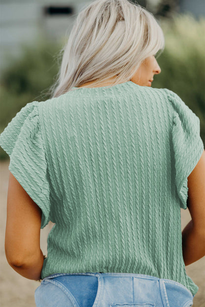 Woman wearing a green textured top with blurred background