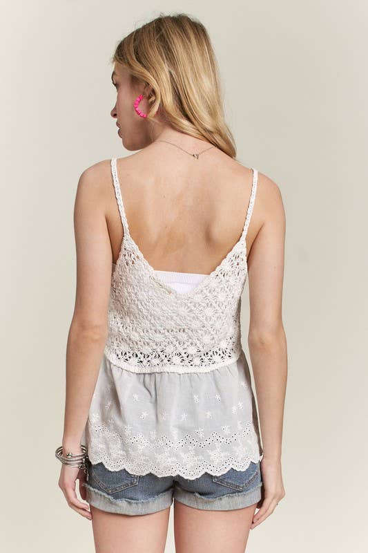 Woman wearing a white lace top and denim shorts on a beige background