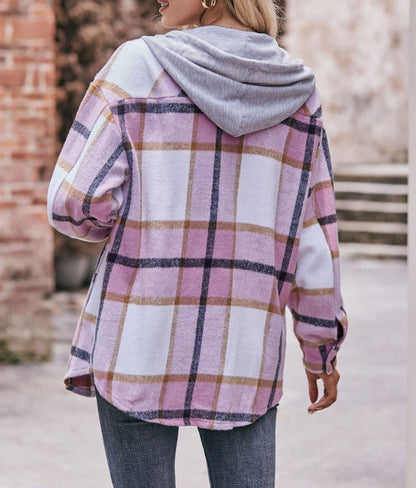 Person wearing a pink and gray plaid hoodie with a brick wall background