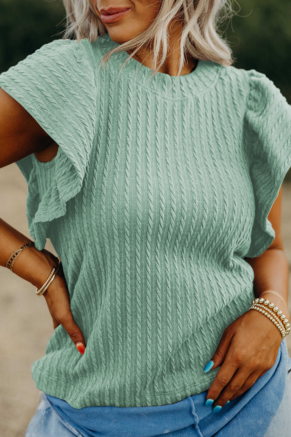 Person wearing a light green knitted sweater with short sleeves.