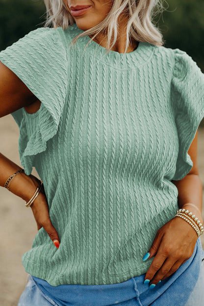 Person wearing a light green knitted sweater with short sleeves.