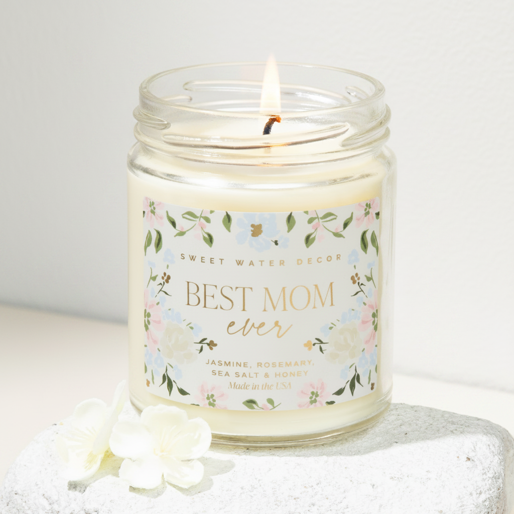 Candle in a jar labeled 'Best Mom Ever' with floral design on a textured surface.