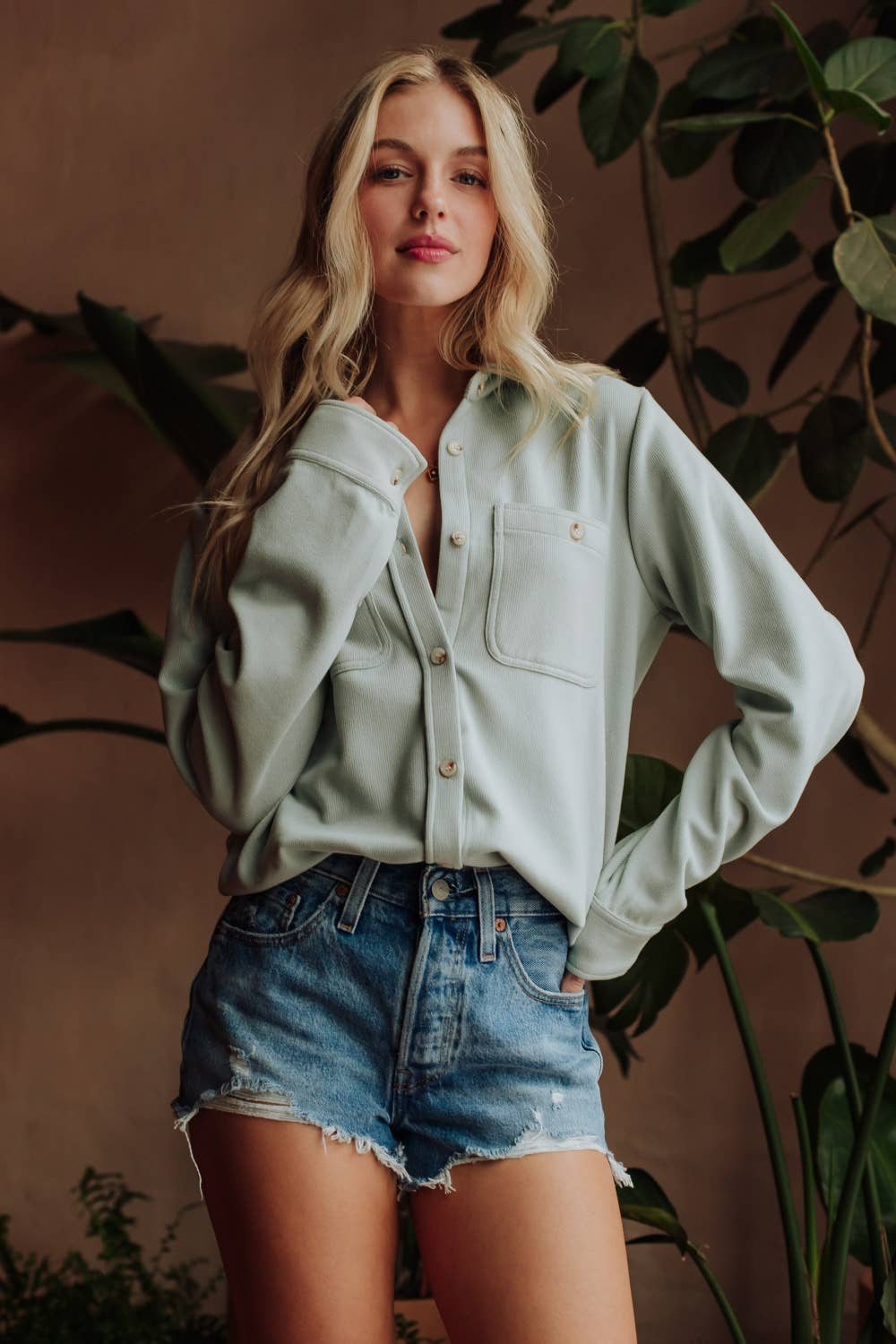 Women's light blue stretchy button-up shirt styled with denim shorts
