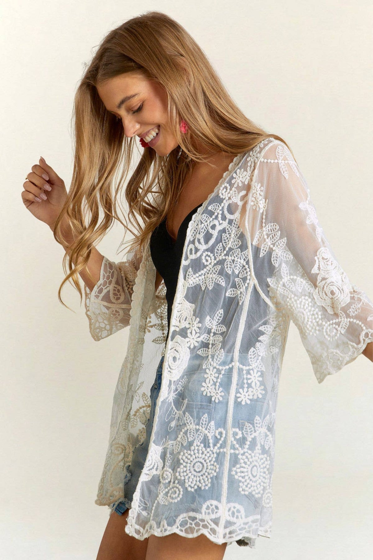 Woman wearing a lace robe over a black top on a white background