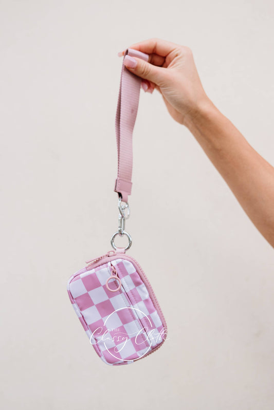Pink checkered pouch with a strap held by a hand against a beige background
