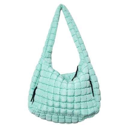 Light blue quilted handbag with black zippers on a white background