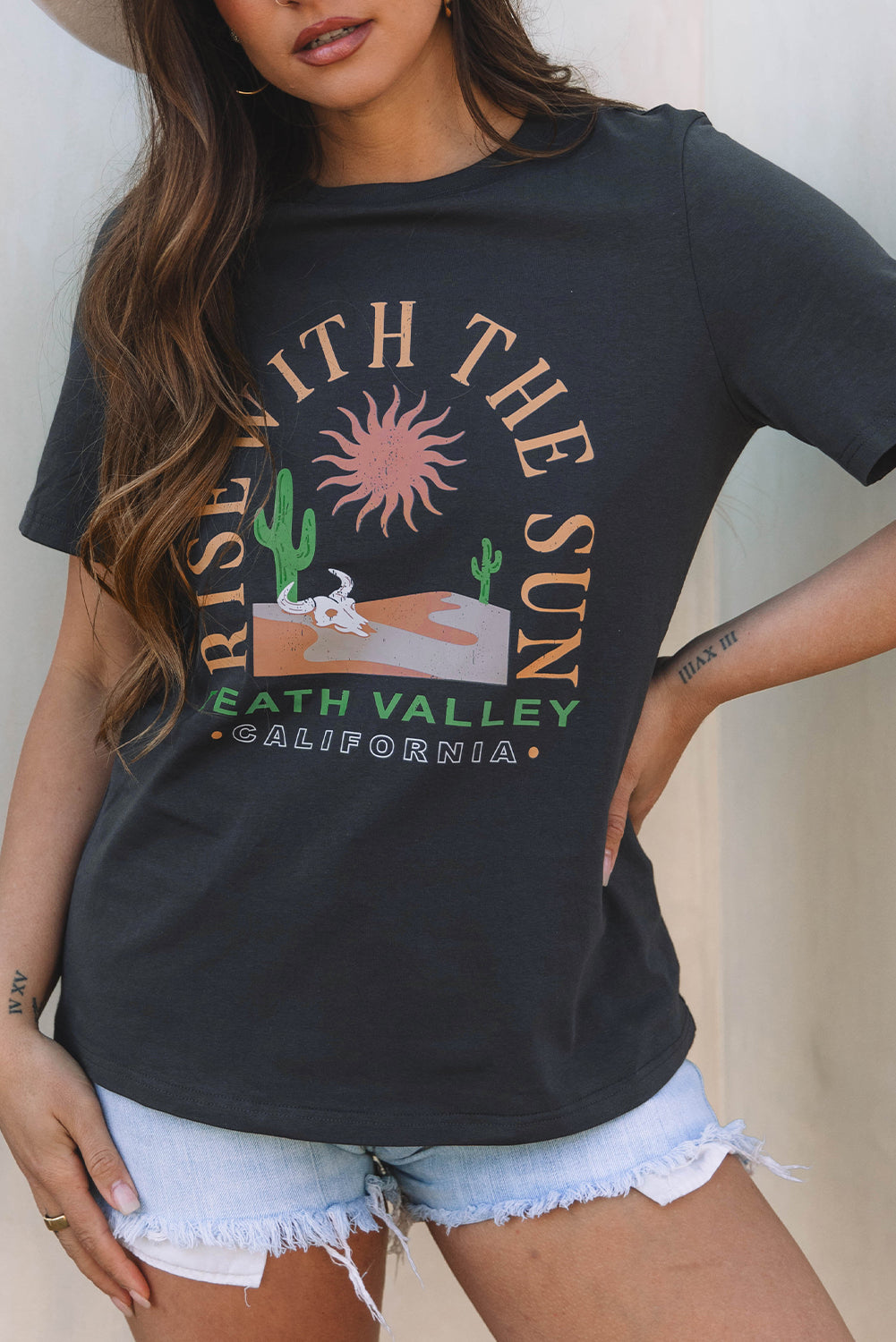 Person wearing a black t-shirt with a graphic design and text, standing against a neutral background.