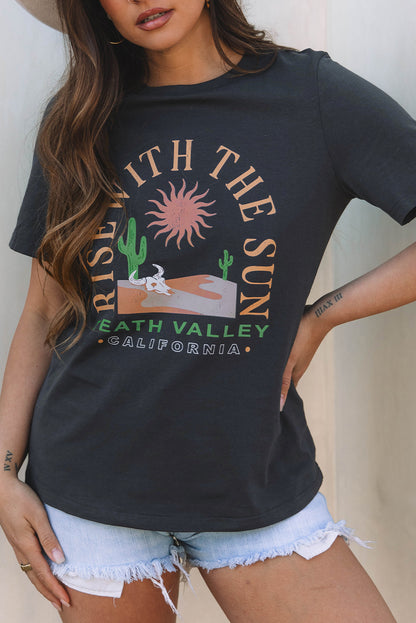 Person wearing a black t-shirt with a graphic design and text, standing against a neutral background.