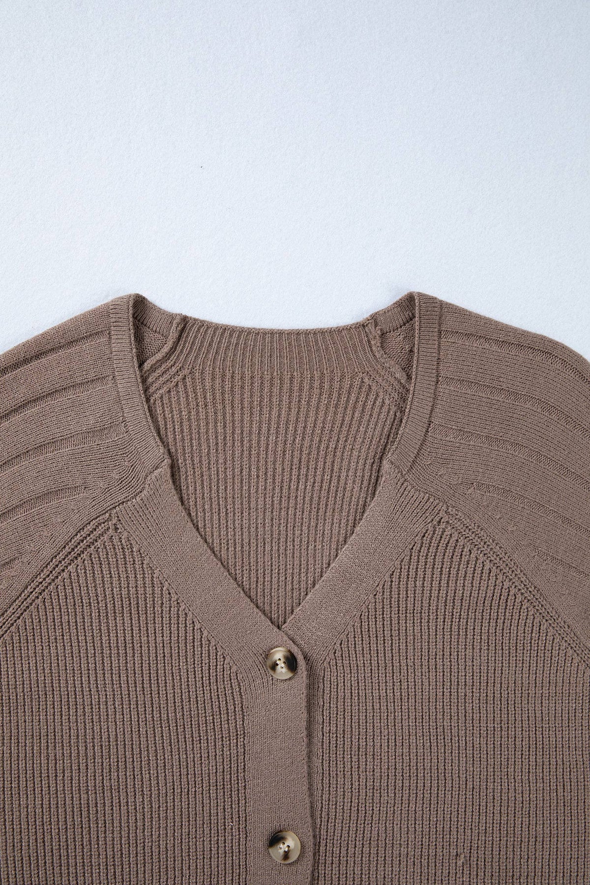 Brown ribbed sweater with buttons on a light blue background