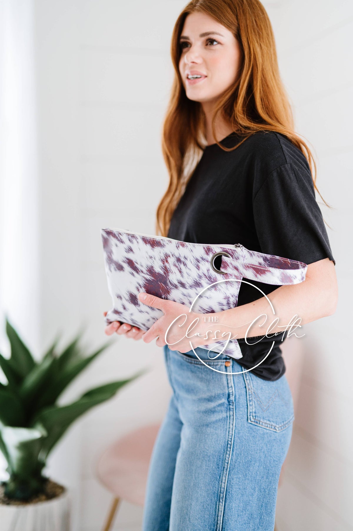 Woman holding a purple and white clutch with a plant in the background