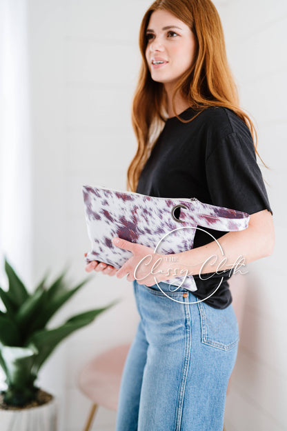 Woman holding a purple and white clutch with a plant in the background