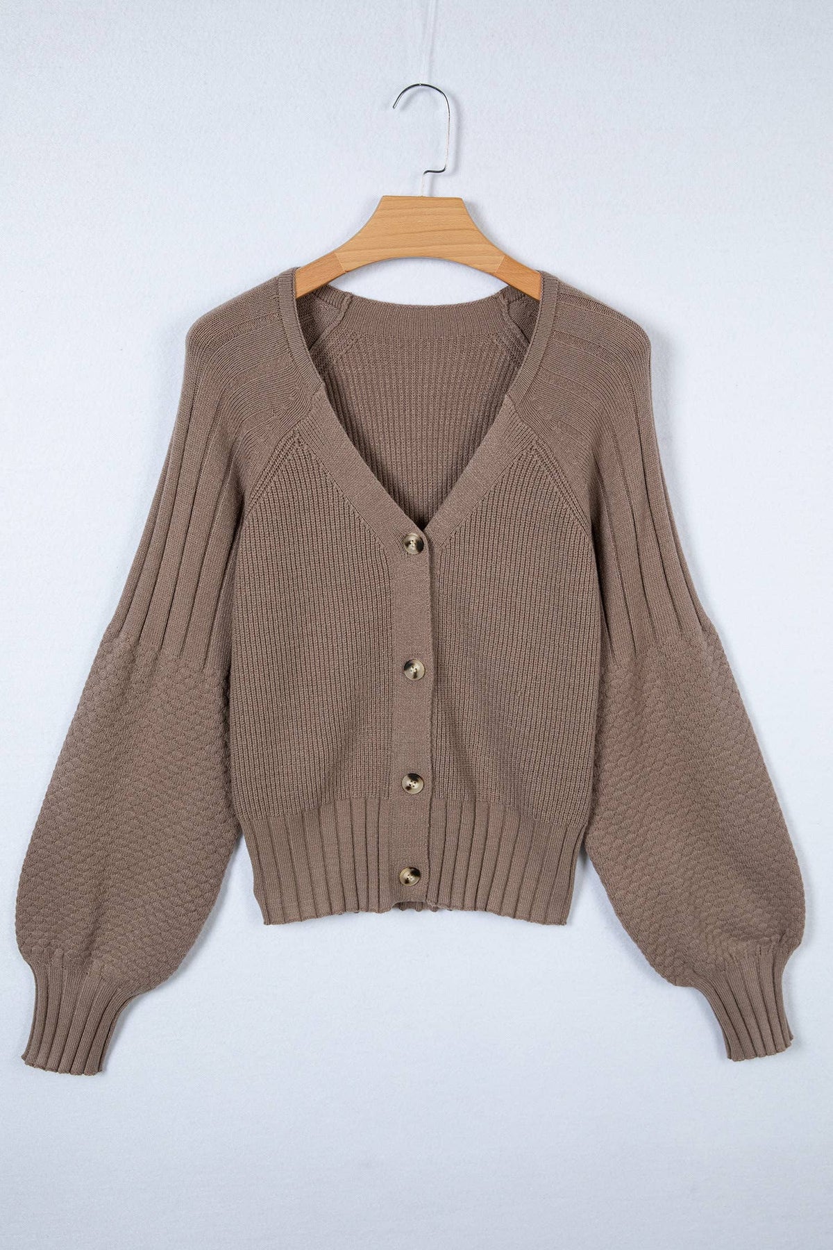 Brown cardigan on a wooden hanger against a white background