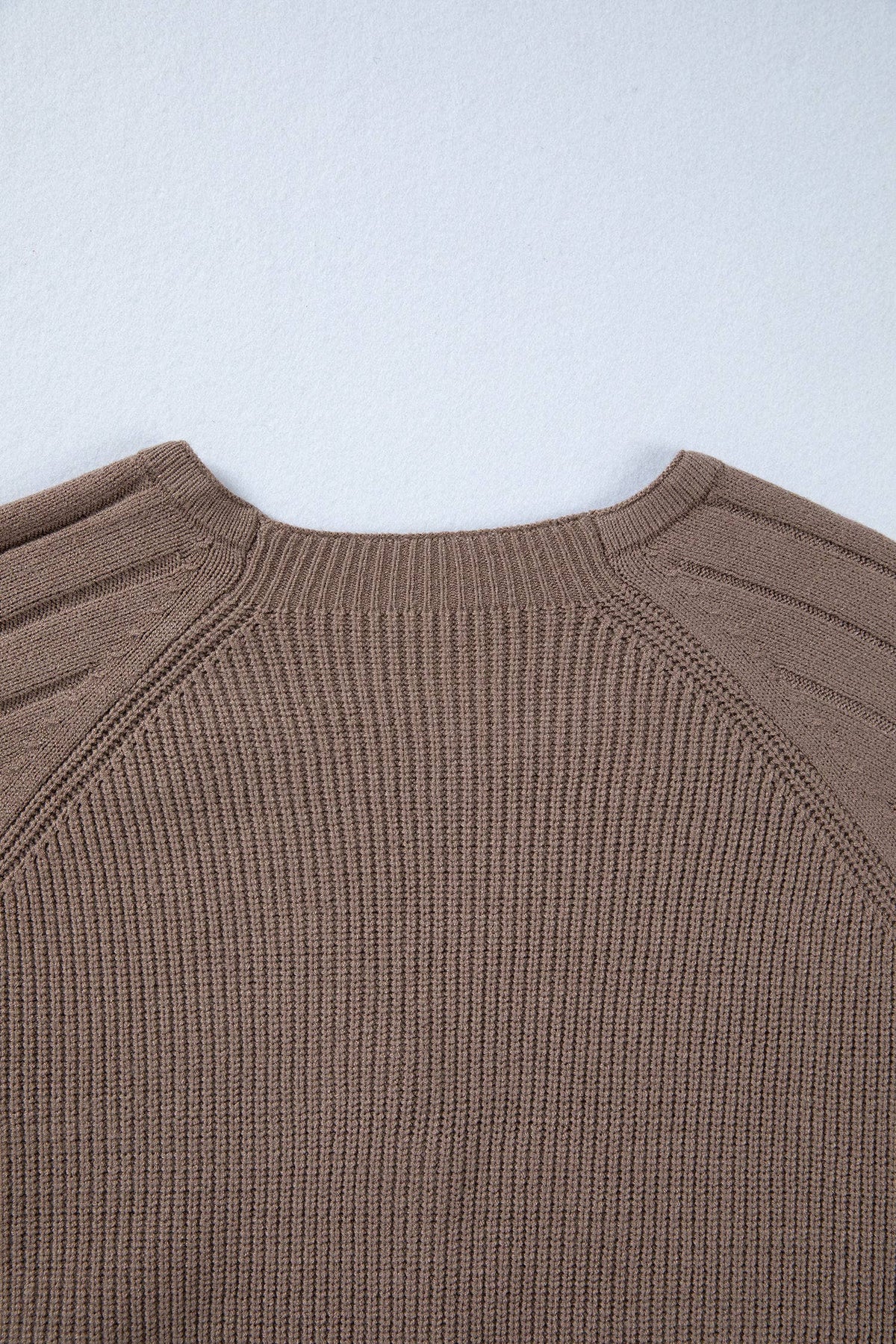 Close-up of a brown ribbed sweater on a light gray background