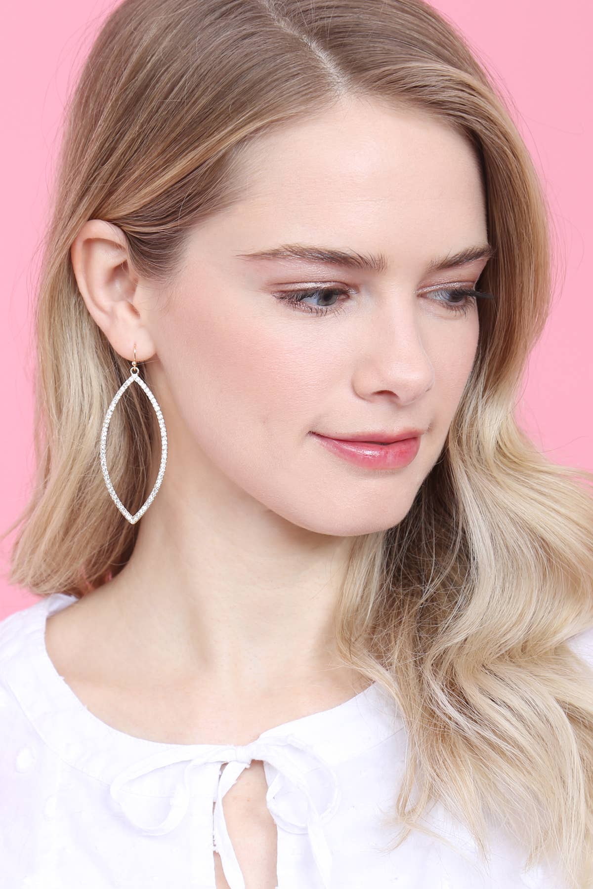Woman wearing a silver hoop earring against a pink background