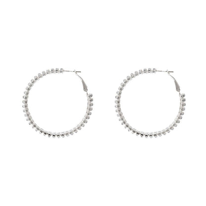 Pair of silver hoop earrings with clear stones on a white background
