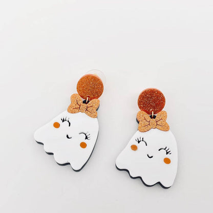 Pair of ghost-shaped earrings with bow details on a light gray background
