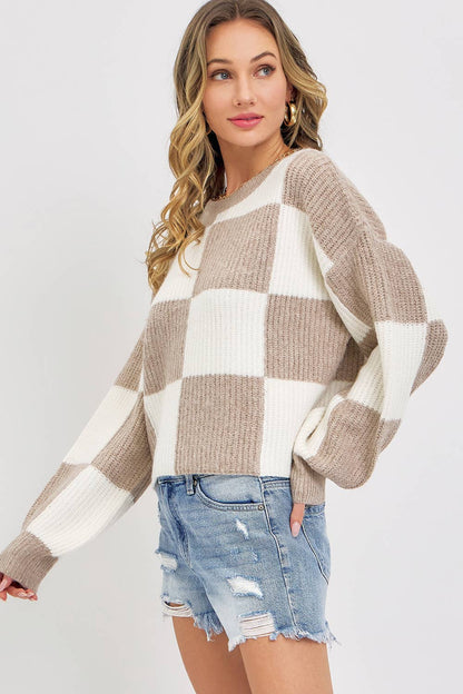 Woman wearing a checkered sweater and denim shorts on a plain background