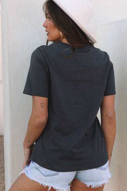 Woman wearing a black t-shirt and denim shorts against a neutral background