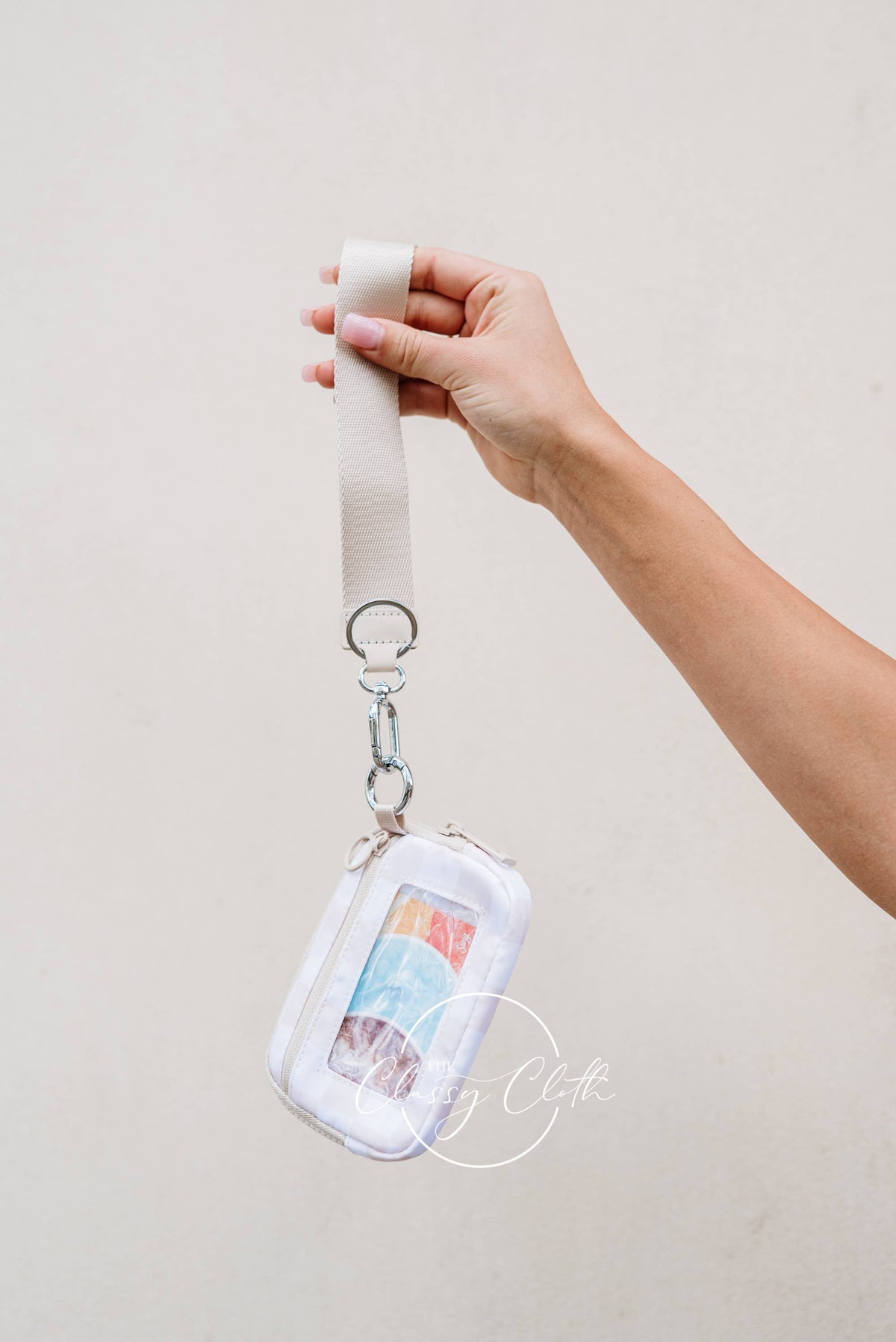 Hand holding a lanyard with a clear pouch against a plain background
