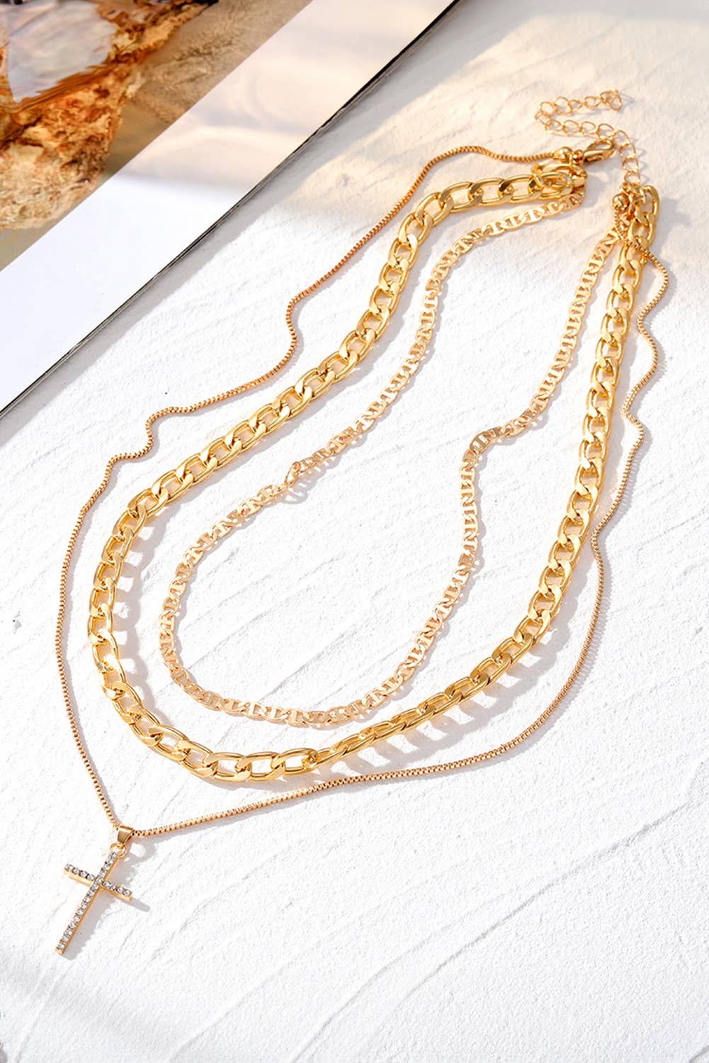 Gold chain necklaces on a textured white surface