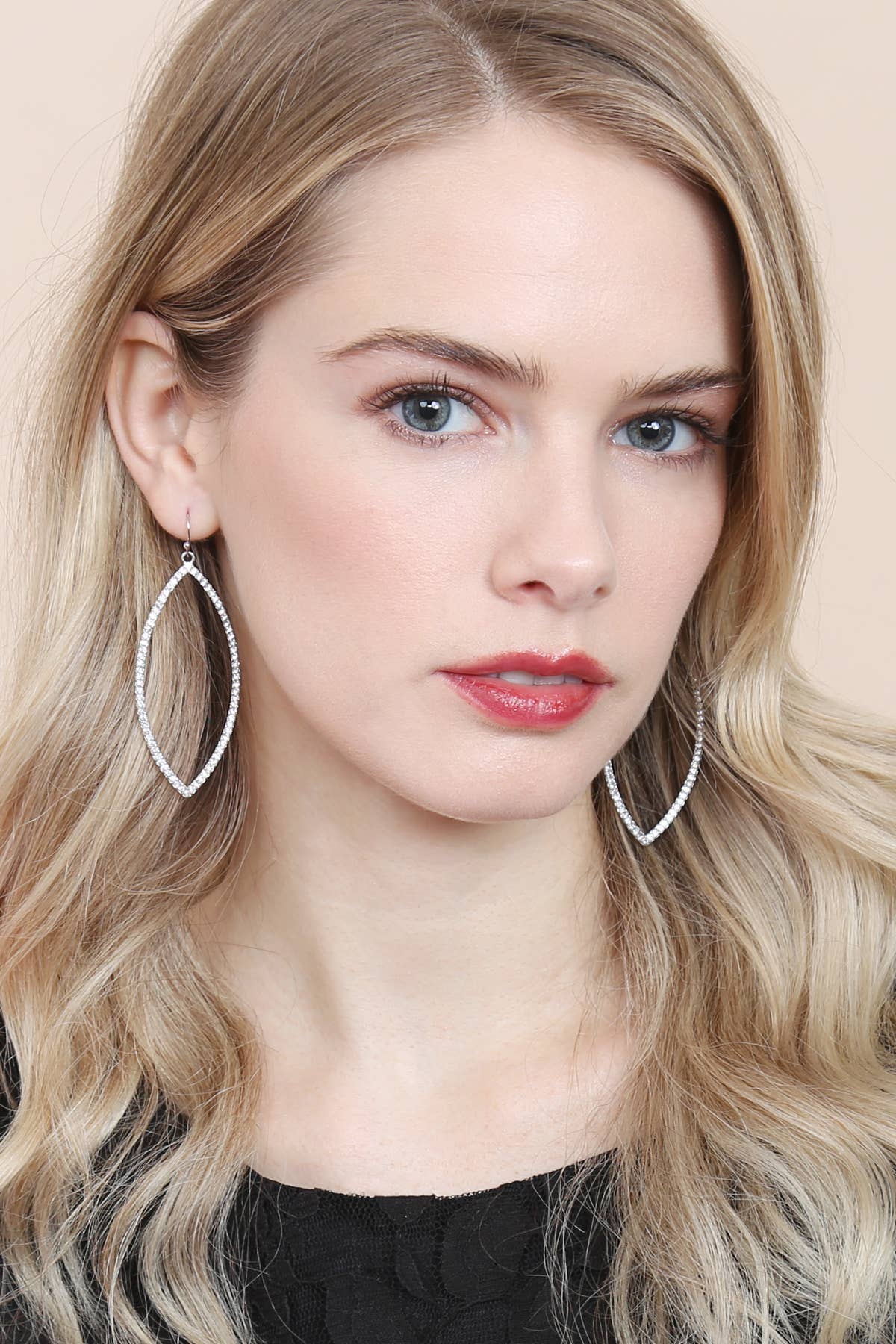 Woman wearing large hoop earrings with a neutral background