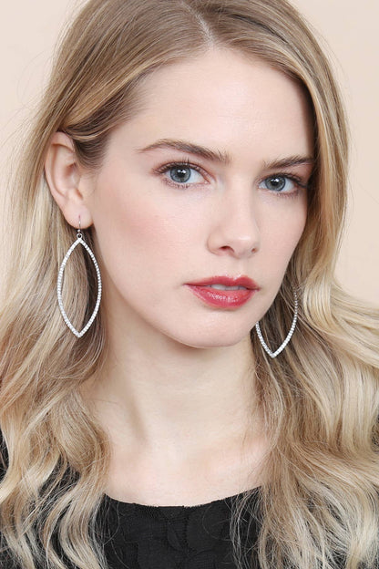 Woman wearing large hoop earrings with a neutral background