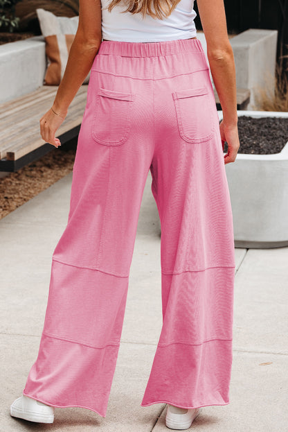 Person wearing pink wide-leg pants and a white top outdoors.