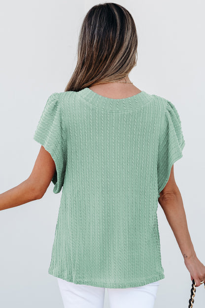Woman wearing a green textured top against a white background