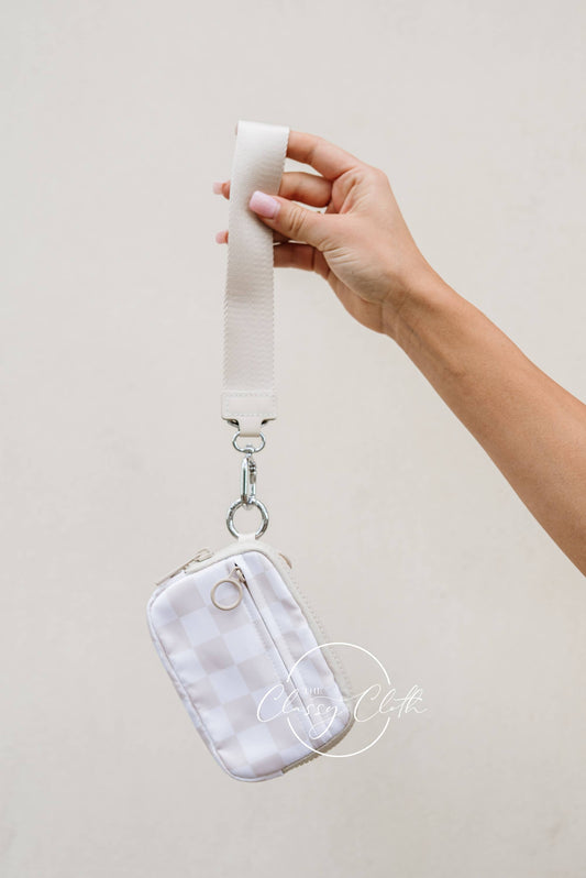 Hand holding a white pouch with a strap against a light background