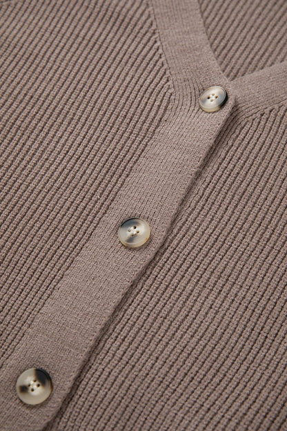 Close-up of a ribbed knit cardigan with buttons on a brown background