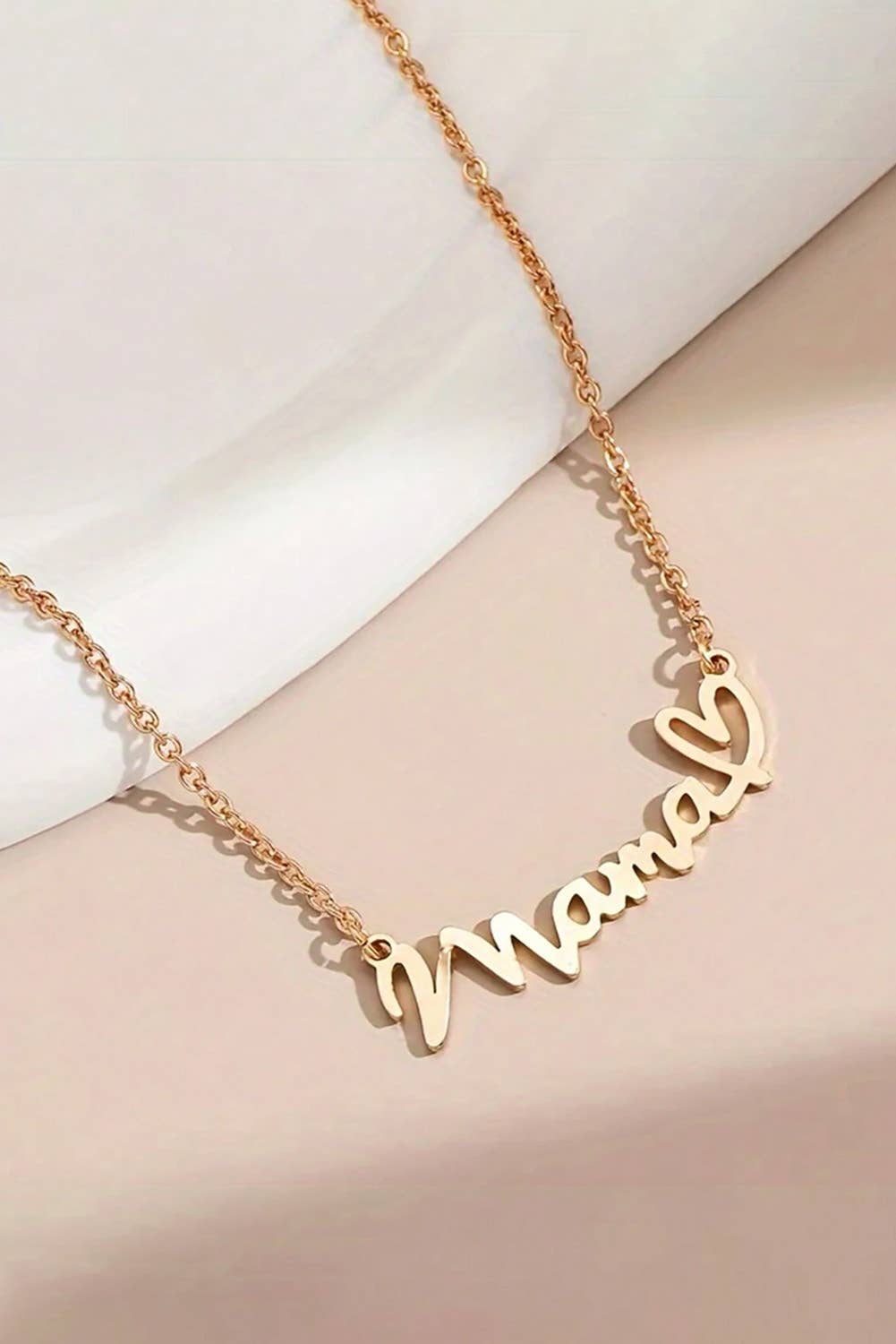 Gold necklace with 'mom' pendant on a white background