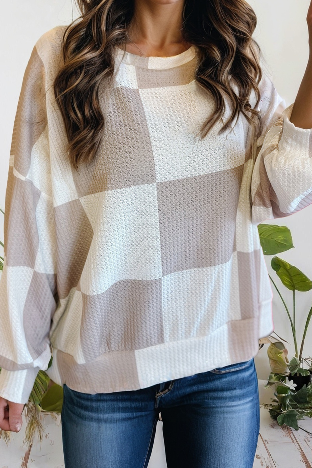 Person wearing a checkered sweater with a neutral color palette, standing indoors.