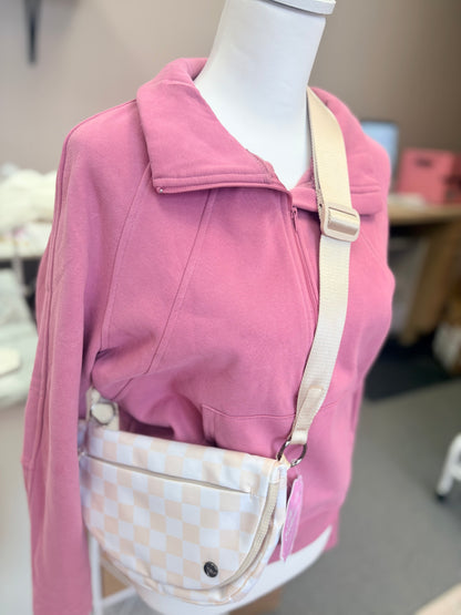 Beige checkered crossbody bag styled with pink quarter zip outfit on mannequin, trendy neutral accessory for casual everyday fashion