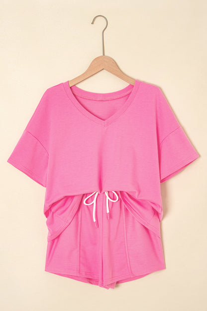 Pink outfit with a top and shorts on a hanger against a beige background