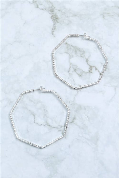 Two silver hoop earrings on a marble surface