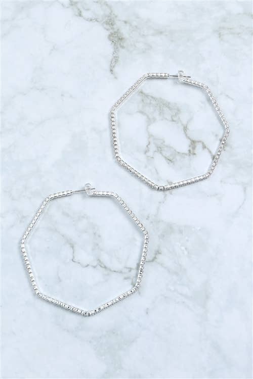 Two silver hoop earrings on a marble surface