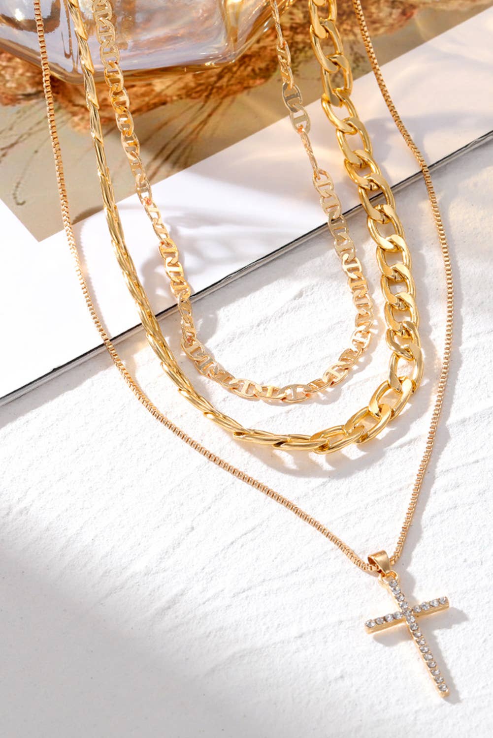 Gold necklaces with a cross pendant on a white surface