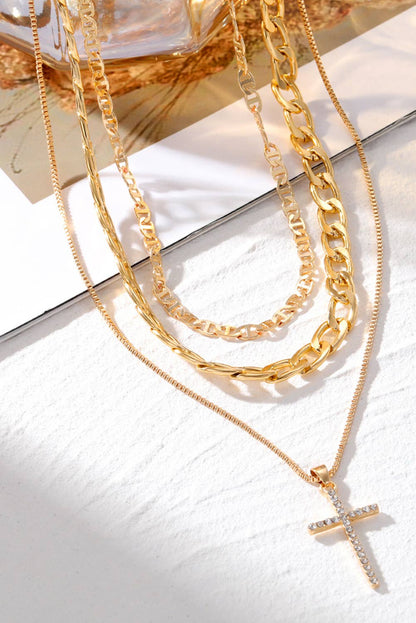 Gold necklaces with a cross pendant on a white surface