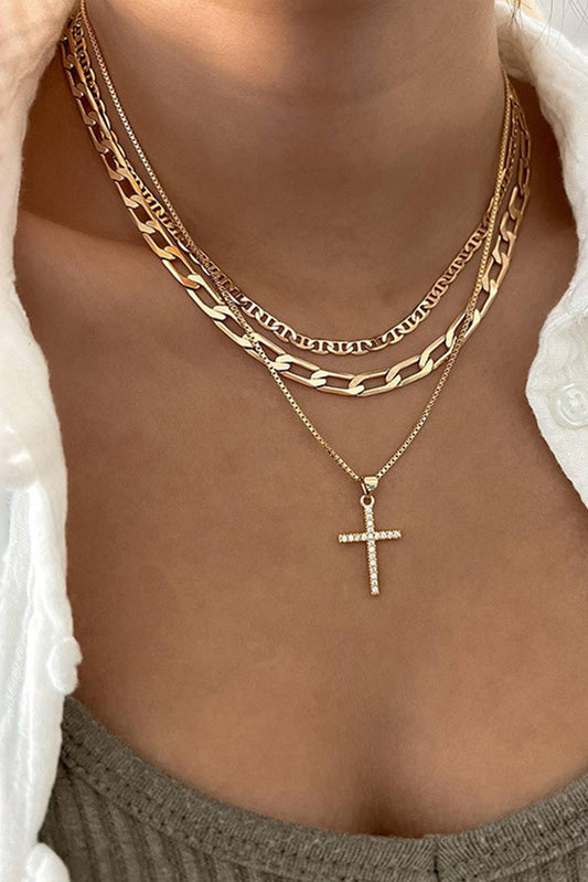Gold chain necklaces with a cross pendant on a person wearing a white jacket.