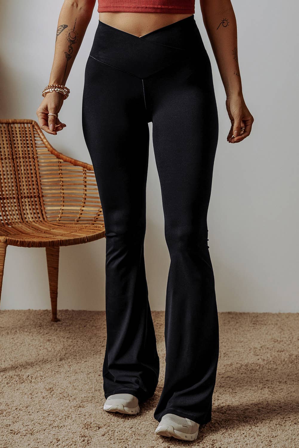Person wearing black flared pants standing in a room with a wooden chair.