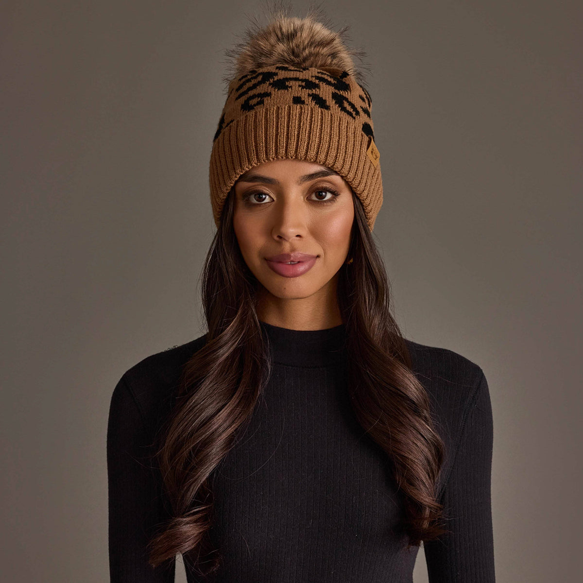 Woman wearing a stylish knit leopard pom pom hat